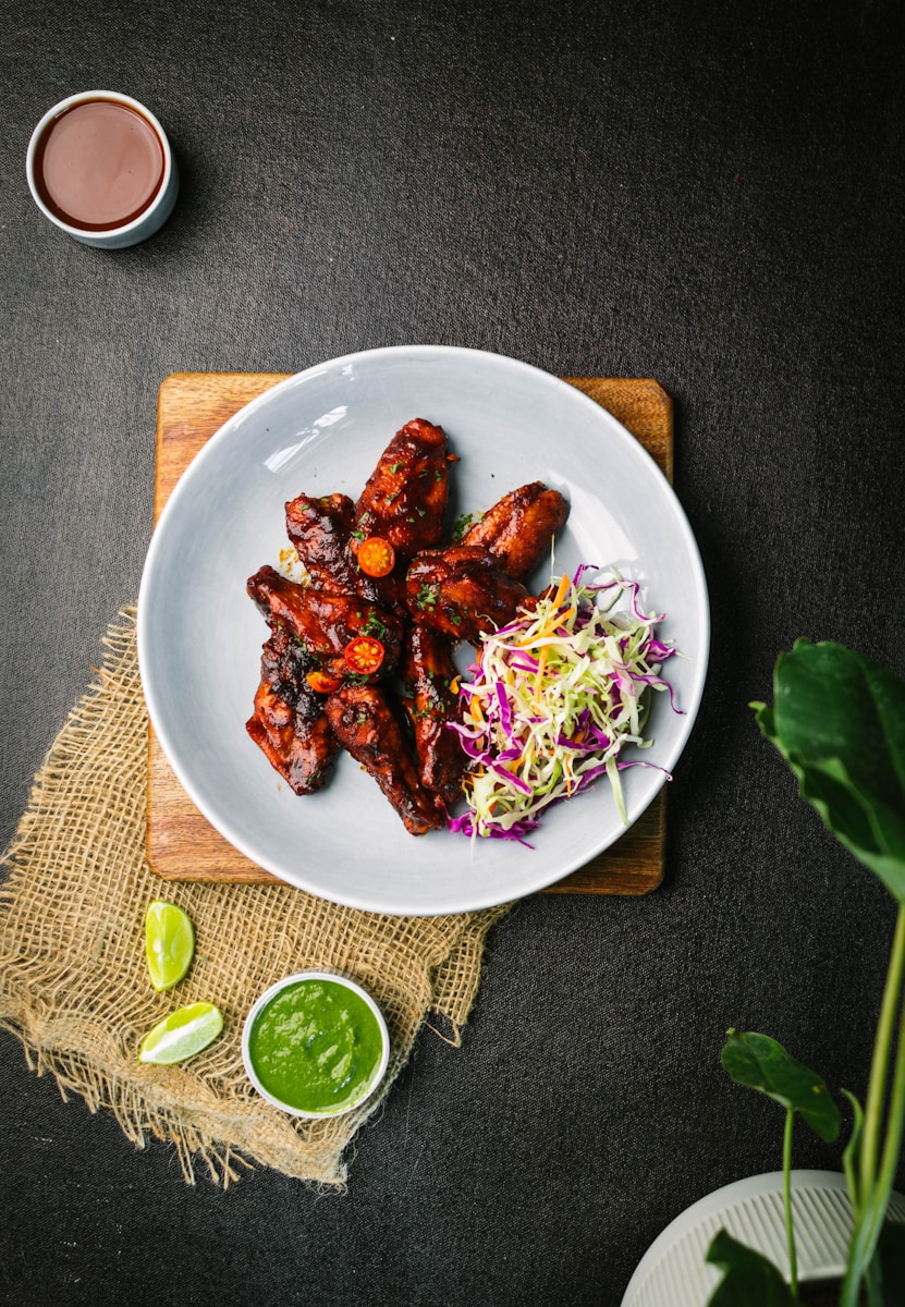 a white plate topped with BBQ chicken wings and cole slaw